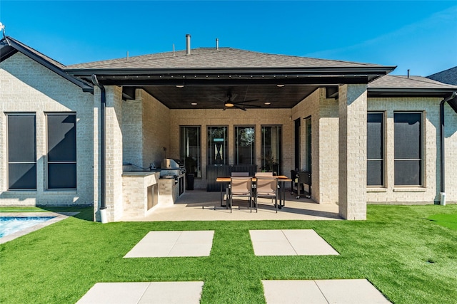 back of house with a lawn, an outdoor kitchen, ceiling fan, and a patio