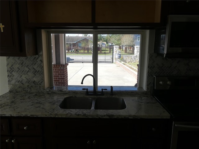 kitchen featuring backsplash, a healthy amount of sunlight, sink, and black range with electric cooktop