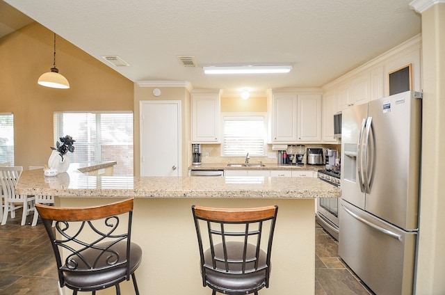 kitchen with a kitchen breakfast bar, white cabinets, hanging light fixtures, and appliances with stainless steel finishes