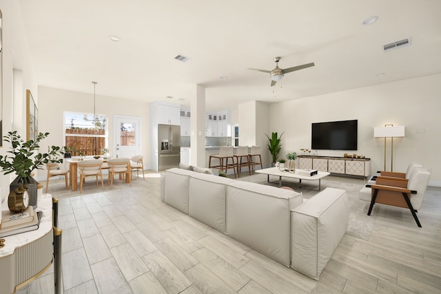 living room featuring light hardwood / wood-style flooring and ceiling fan with notable chandelier