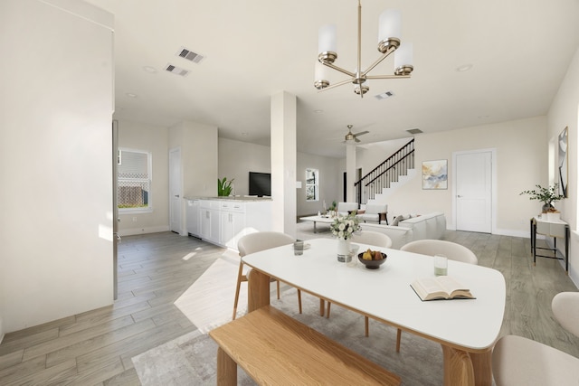 dining room with plenty of natural light, light hardwood / wood-style flooring, and ceiling fan with notable chandelier