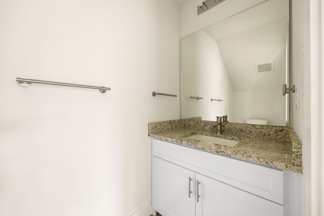 bathroom with vanity, toilet, and vaulted ceiling