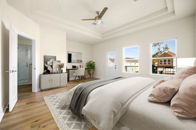 bedroom with a raised ceiling, ceiling fan, and light wood-type flooring