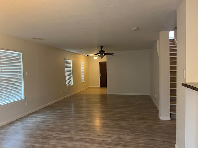 unfurnished living room with ceiling fan and dark wood-type flooring