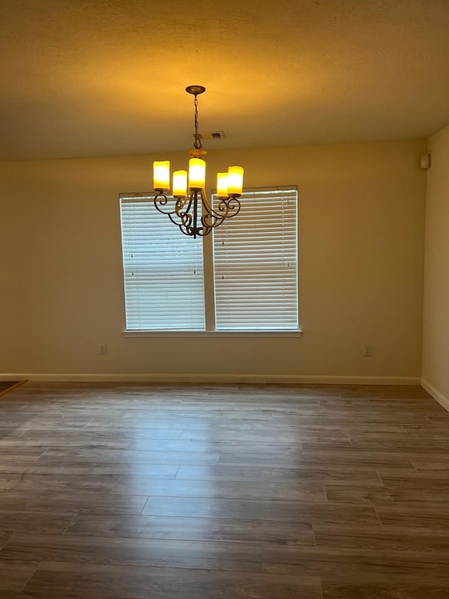 unfurnished room featuring dark wood-type flooring and a notable chandelier