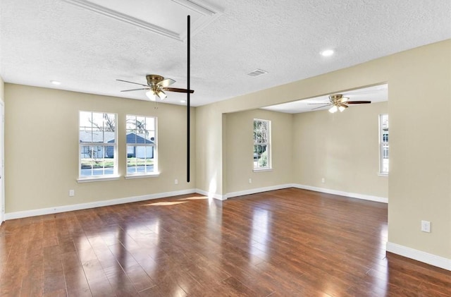 unfurnished living room with a textured ceiling, plenty of natural light, and dark wood-type flooring