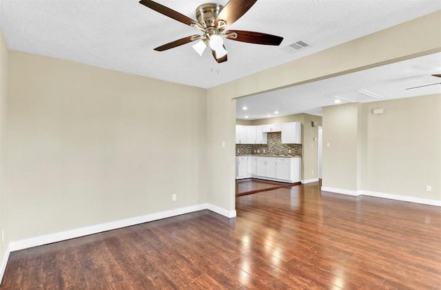 unfurnished living room featuring ceiling fan, dark hardwood / wood-style flooring, and a textured ceiling