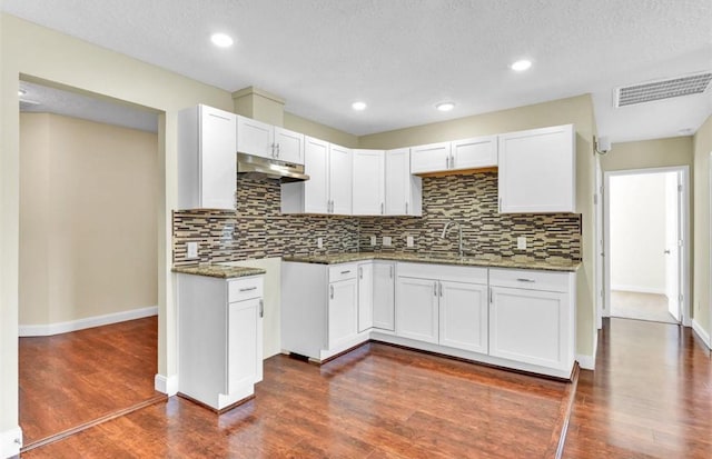 kitchen featuring white cabinets, dark stone counters, and a textured ceiling