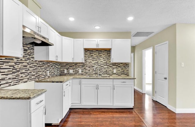 kitchen with white cabinets, sink, dark hardwood / wood-style floors, decorative backsplash, and light stone countertops