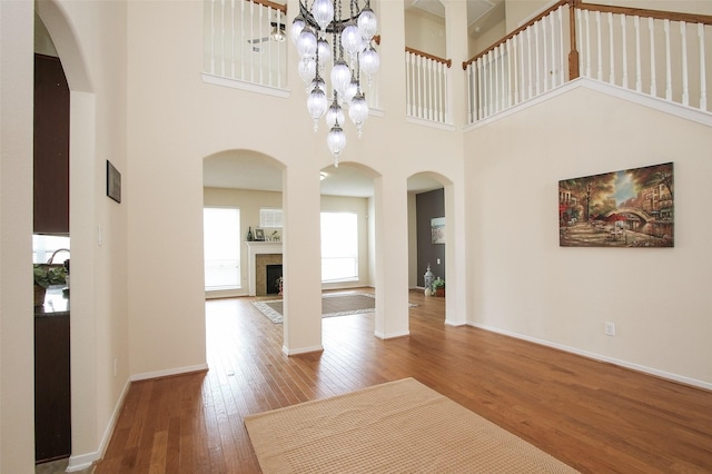 interior space featuring wood-type flooring, a towering ceiling, and an inviting chandelier