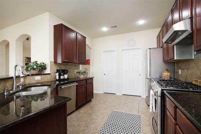 kitchen featuring sink, stainless steel appliances, dark stone counters, decorative backsplash, and exhaust hood