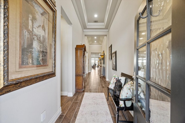 hallway with a tray ceiling and ornamental molding