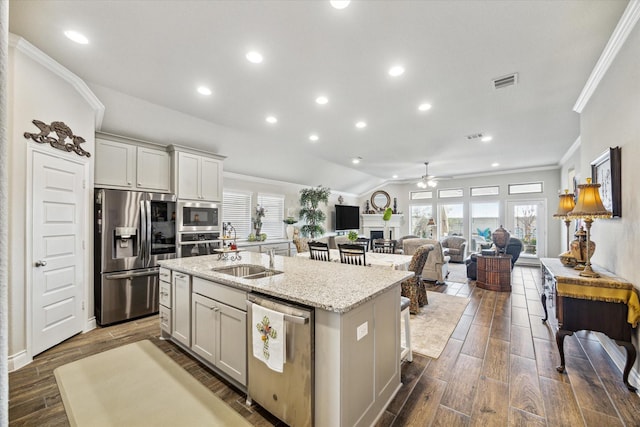 kitchen with sink, ceiling fan, an island with sink, light stone counters, and stainless steel appliances