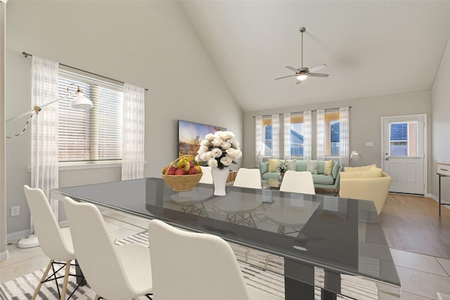 dining room with light wood-type flooring, high vaulted ceiling, ceiling fan, and a healthy amount of sunlight