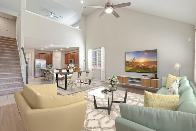 living room with ceiling fan, light hardwood / wood-style flooring, and high vaulted ceiling