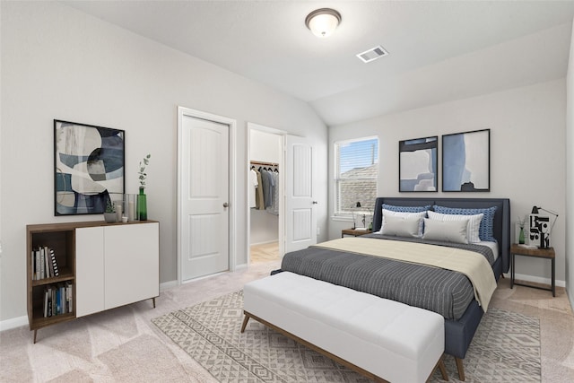 bedroom with a walk in closet, light carpet, a closet, and lofted ceiling