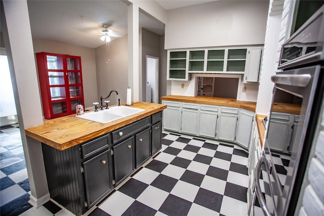 kitchen with ceiling fan, white cabinetry, butcher block countertops, and sink