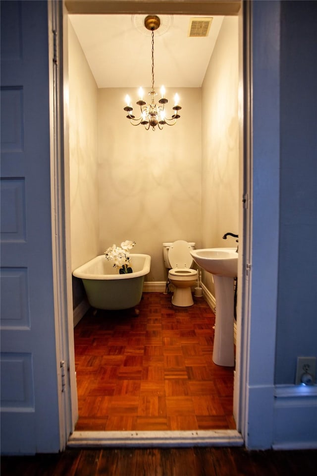 bathroom featuring toilet, parquet flooring, a tub, and a chandelier