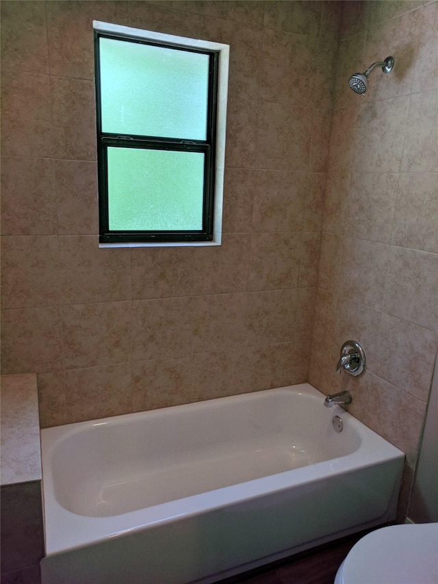 bathroom featuring toilet and tiled shower / bath