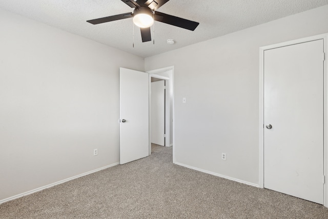 unfurnished bedroom with ceiling fan, light colored carpet, and a textured ceiling