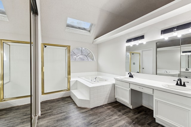 bathroom with hardwood / wood-style floors, vanity, shower with separate bathtub, and vaulted ceiling with skylight