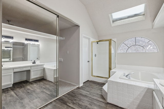 bathroom featuring lofted ceiling with skylight, vanity, hardwood / wood-style flooring, and shower with separate bathtub