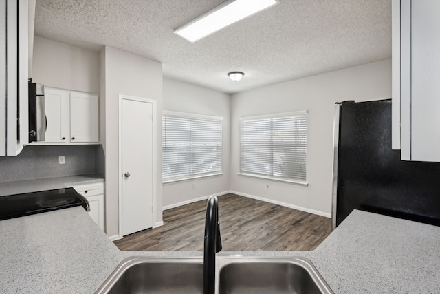 kitchen featuring stainless steel fridge, sink, white cabinets, and a textured ceiling