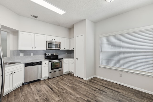 kitchen with a textured ceiling, backsplash, white cabinetry, and stainless steel appliances