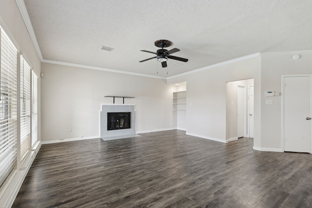 unfurnished living room featuring ceiling fan, dark hardwood / wood-style flooring, crown molding, a textured ceiling, and a tiled fireplace