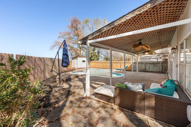 view of patio / terrace featuring a fenced in pool, a storage unit, and ceiling fan