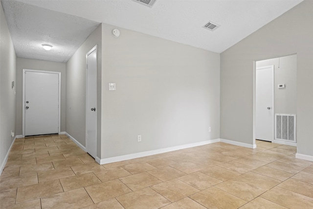 unfurnished room featuring lofted ceiling and a textured ceiling