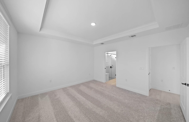 carpeted spare room with a raised ceiling and ornamental molding