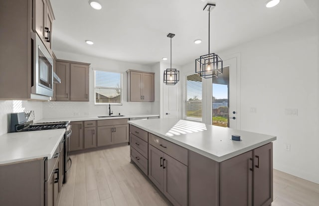 kitchen with stainless steel appliances, a healthy amount of sunlight, sink, a kitchen island, and hanging light fixtures