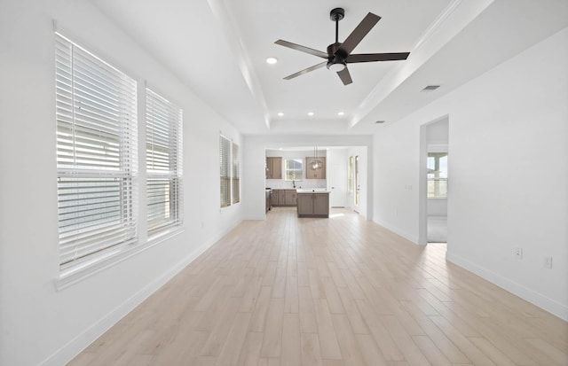 unfurnished living room featuring light hardwood / wood-style flooring, a raised ceiling, ceiling fan, and crown molding