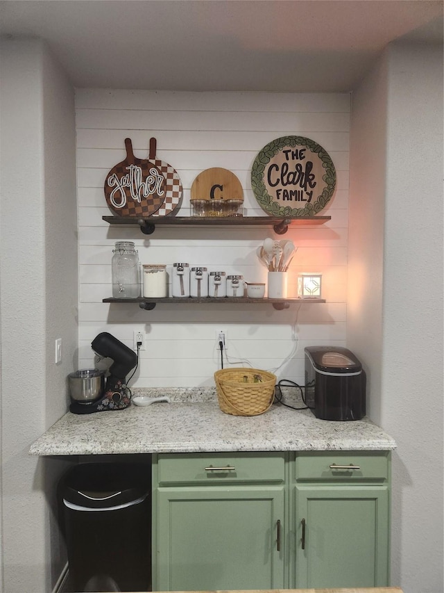 bar featuring light stone countertops and green cabinetry