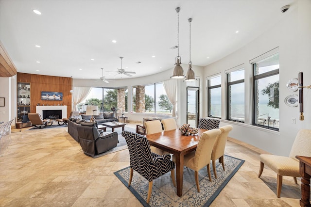 dining area with ceiling fan and a large fireplace