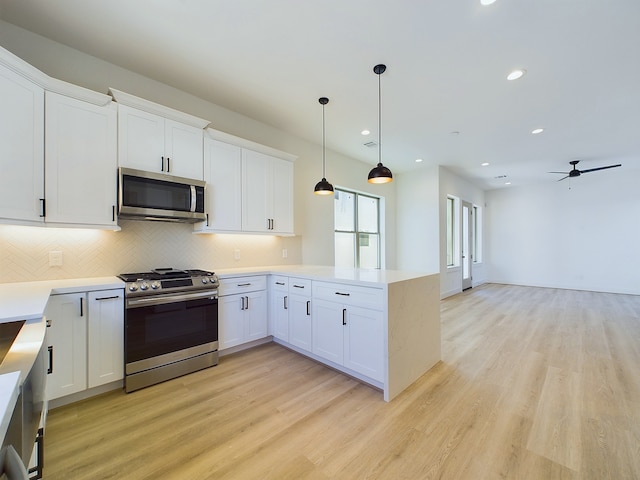 kitchen with kitchen peninsula, ceiling fan, stainless steel appliances, hanging light fixtures, and white cabinets