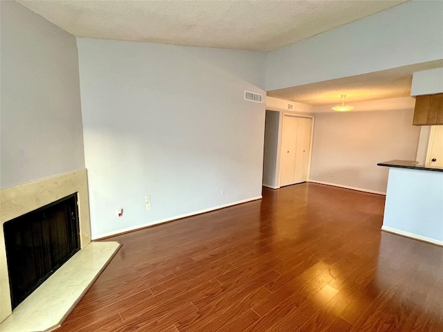 unfurnished living room featuring a textured ceiling, a fireplace, and dark wood-type flooring