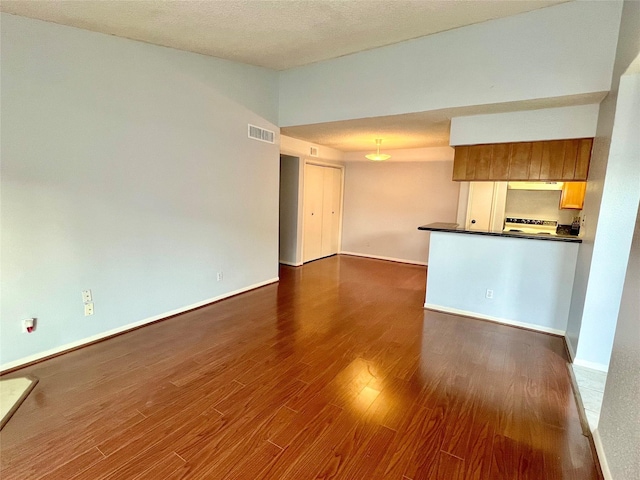 unfurnished living room with a textured ceiling and dark hardwood / wood-style floors