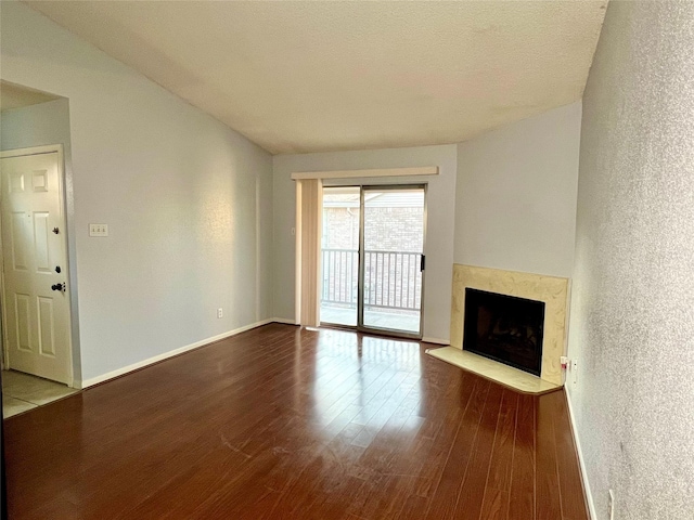 unfurnished living room with a fireplace, a textured ceiling, and hardwood / wood-style flooring