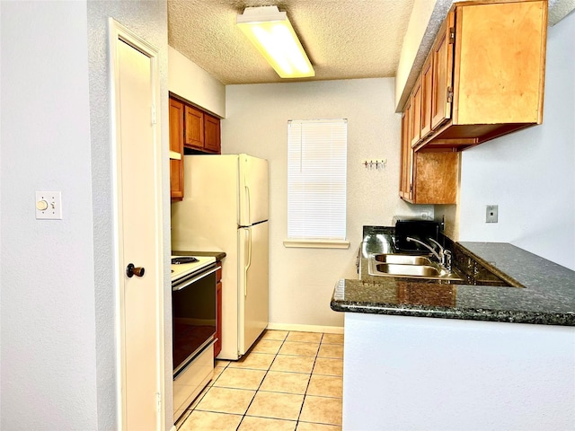 kitchen with a textured ceiling, sink, light tile patterned floors, and white appliances