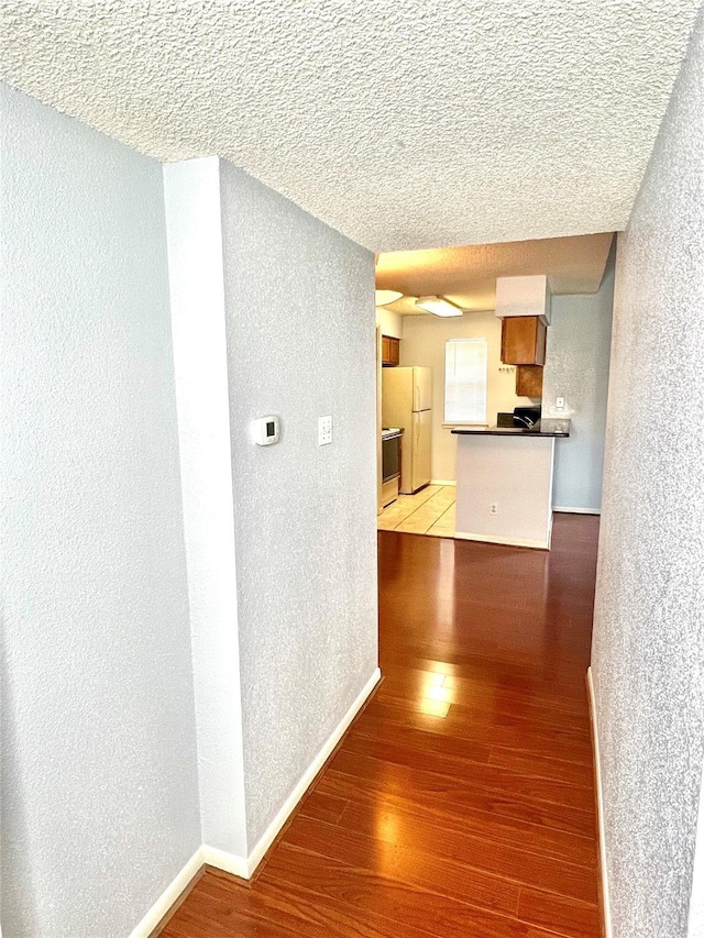 hall featuring a textured ceiling and light hardwood / wood-style flooring