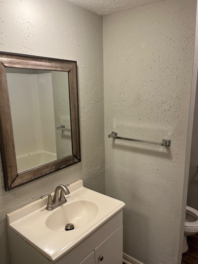 bathroom featuring vanity, a textured ceiling, and toilet