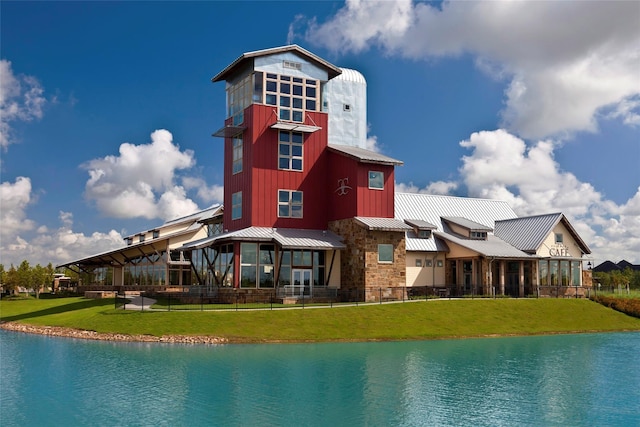 rear view of house featuring a yard and a water view