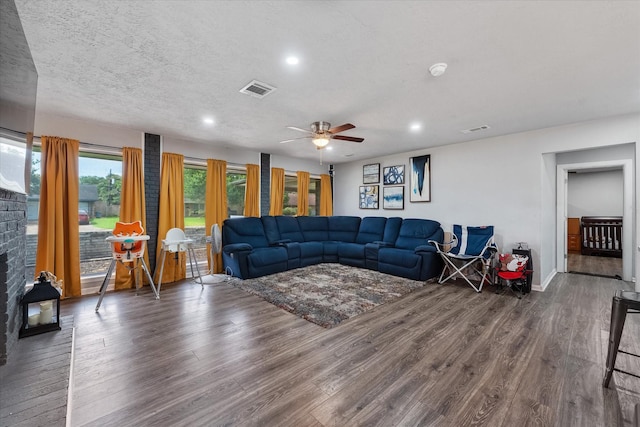 living room featuring dark hardwood / wood-style floors, ceiling fan, and a textured ceiling