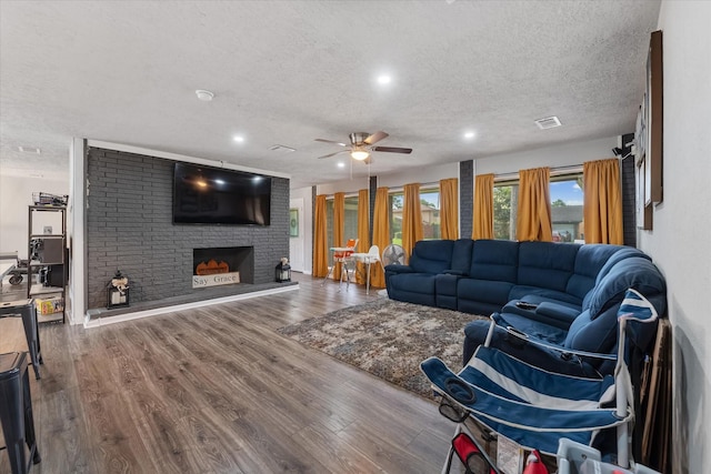 living room with a fireplace, hardwood / wood-style floors, a textured ceiling, and ceiling fan