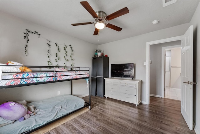 bedroom with a textured ceiling, hardwood / wood-style flooring, and ceiling fan