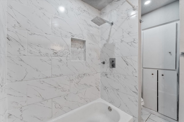 bathroom featuring toilet and tiled shower / bath