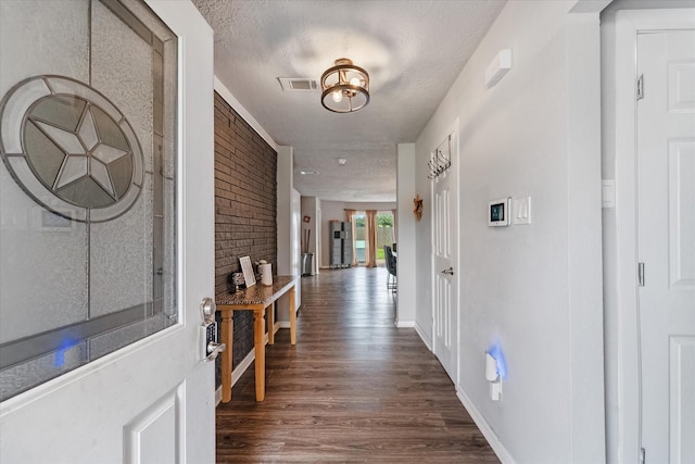 corridor featuring dark hardwood / wood-style flooring, brick wall, and a textured ceiling