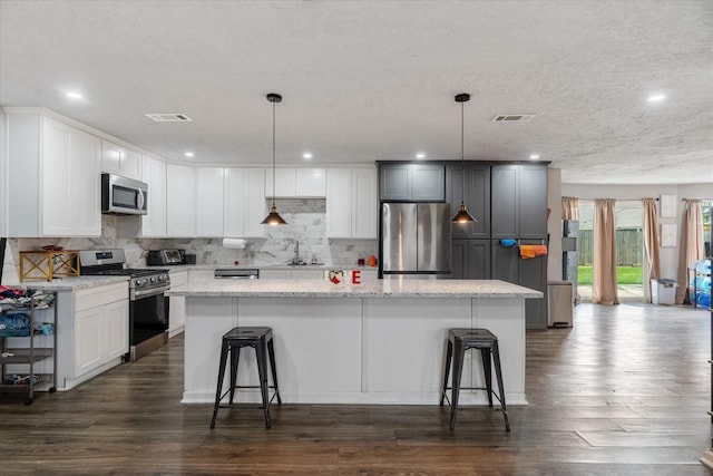 kitchen featuring white cabinetry, light stone counters, a center island, and stainless steel appliances